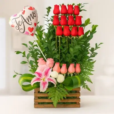 Arreglo Floral Exótico Primaveral - Flores Tropicales - Si conquistar su corazón es lo que deseas, este diseño floral será tu aliado, envía este bello arreglo el cual se encuentra elaborado en una base de madera o similar, compuesto de 18 rosas en tonos rojo y rosado, un lirio y follajes verdes. El diseño incluye un globo metalizado “Te Amo”. Sugerimos que acompañes este diseño con chocolates, peluches, globos o vinos para hacer aún más especial tu detalle, en el siguiente paso de la compra puedes agregar a tu orden estos productos si lo deseas. - Floresco