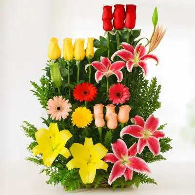 Arreglo Floral Exótico Paraíso - Flores Tropicales - Las flores son la expresión más pura y el mejor canal por medio del cual puedes demostrar tus sentimientos, envía esta hermosa combinación de 18 rosas en tonos rojo, amarillo y rosado, junto con lirios, gerberas y follajes verdes. Está elaborado sobre una base de madera. Sugerimos que acompañes este diseño con chocolates, peluches, globos o vinos para hacer aún más especial tu detalle, en el siguiente paso de la compra puedes agregar a tu orden estos productos si lo deseas. - Floresco