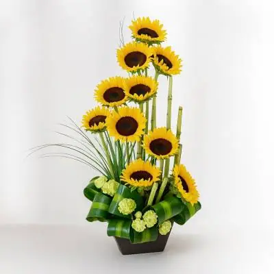 Arreglo con Girasoles Sunna - Flores Tropicales - Llena de luz y alegría su día, sorprende a ese ser especial enviando este lindo diseño floral elaborado sobre una base de madera, está compuesto de 10 girasoles y follajes verdes. Sugerimos que acompañes este diseño con chocolates, peluches o vinos para hacer aún más especial tu detalle, en el siguiente paso de la compra puedes agregar a tu orden estos productos si lo deseas. - Floresco